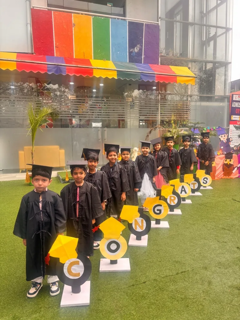 Graduating pre-schoolers in caps and gowns celebrating on the school lawn