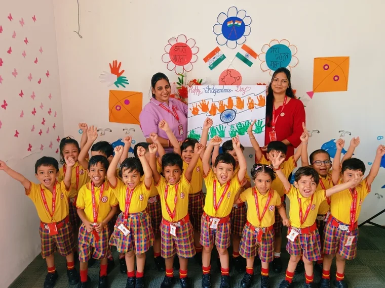 Teachers and children at Red Butterfly Play School celebrating Independence Day with a handprint flag chart